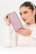 Mujer con suéter blanco sostiene cartera lila de piel con logo Moixx dorado sobre fondo blanco