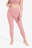 Mujer vestida con conjunto deportivo rosa, leggins y top crop, fondo blanco